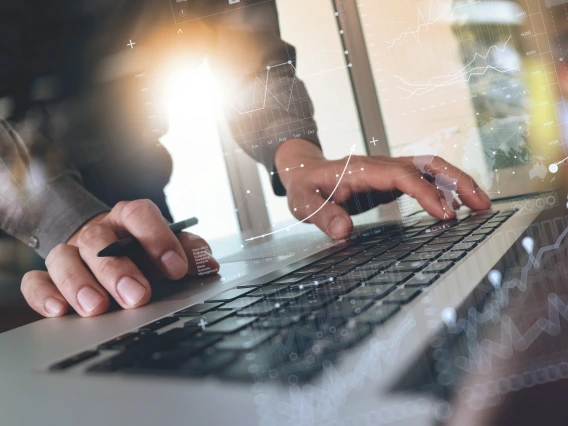 Person with pen in one hand and typing with another hand