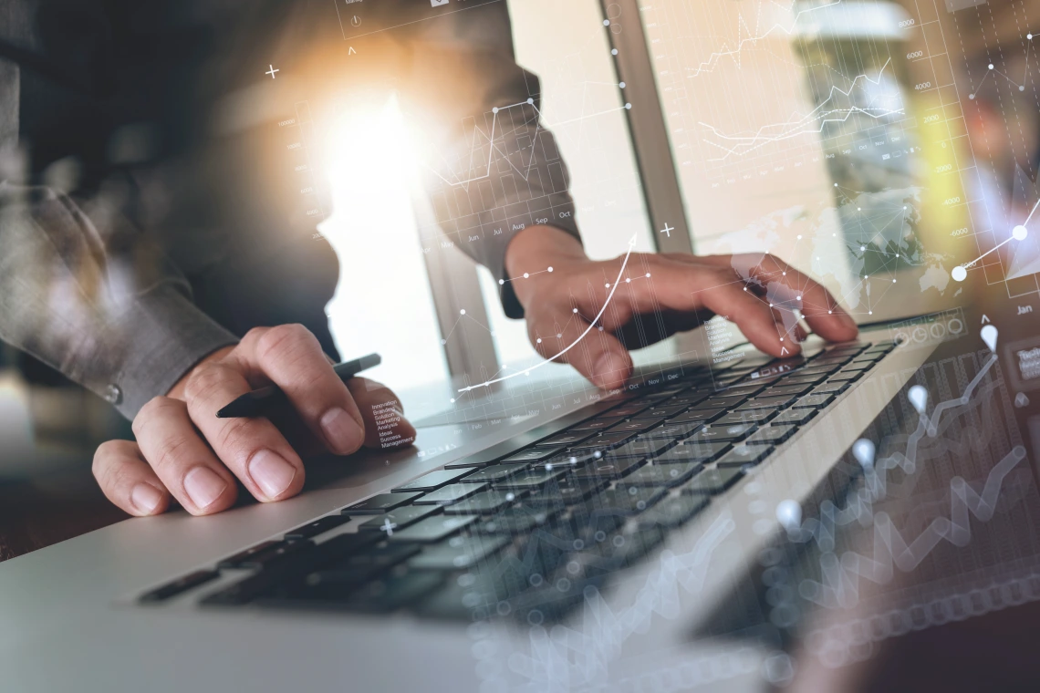 Person with pen in one hand and typing with another hand